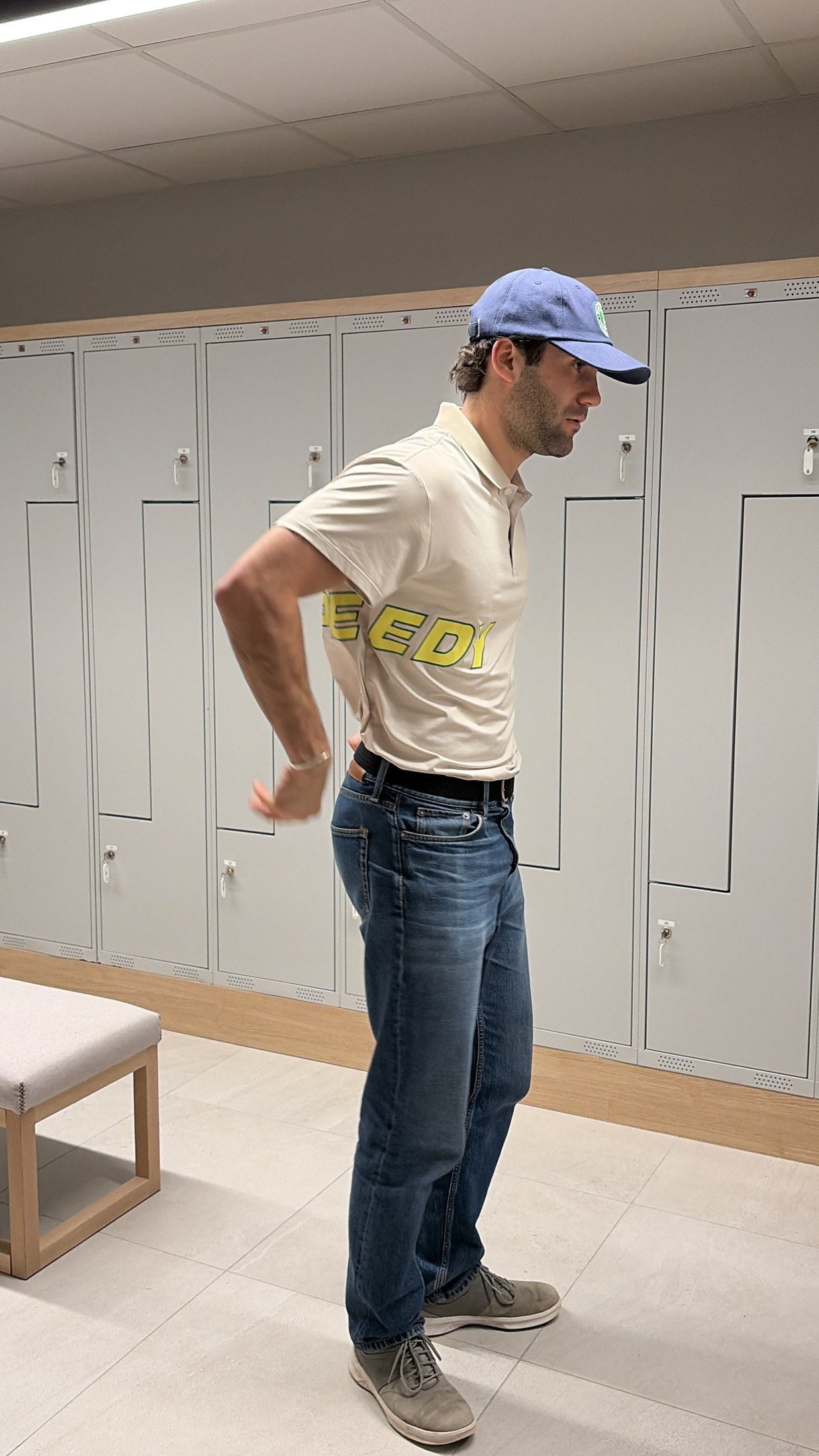 Athlete wearing the cream SPEEDY debut polo, showing the yellow side wordmark